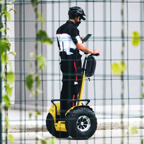 Photo of a security guard on a rugged Segway looking at his mobile phone