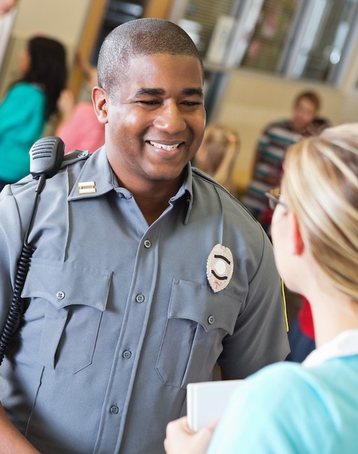 Photo of a security guard smiling to a woman in front of him in a busy room