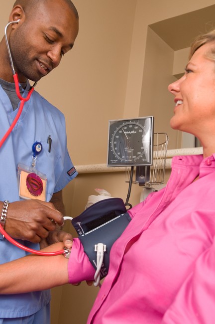Photo of a nurse taking blood pressure to a smiling middle-aged woman